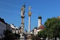 Säule des Tiburtiusbrunnen (vorne links) und barocke Dreifaltigkeitssäule auf dem Theresienplatz in Straubing | Nachfolgende Gesteinsbenennungen nach Lehrberger, G. (2024): Exkursionsführer Straubing 2024